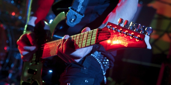 Eine rot leuchtende E-Gitarre der Marke Ibanez während eines Konzerts