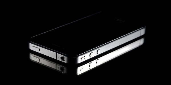 Ein schwarzes iPhone auf schwarzer, spiegelnder Oberfläche