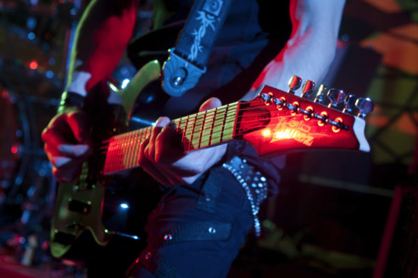 Eine rot reflektierende E-Gitarre der Marke Ibanez während eines Konzerts