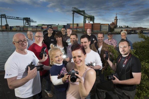Eine Gruppe von Fotografen beim Hafenspaziergang vor der Kulisse des Containerhafens